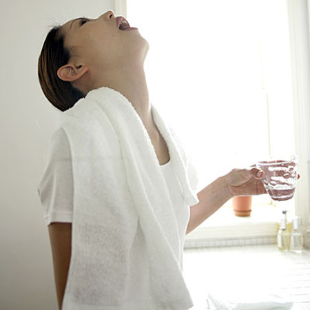 Side profile of a young woman gargling