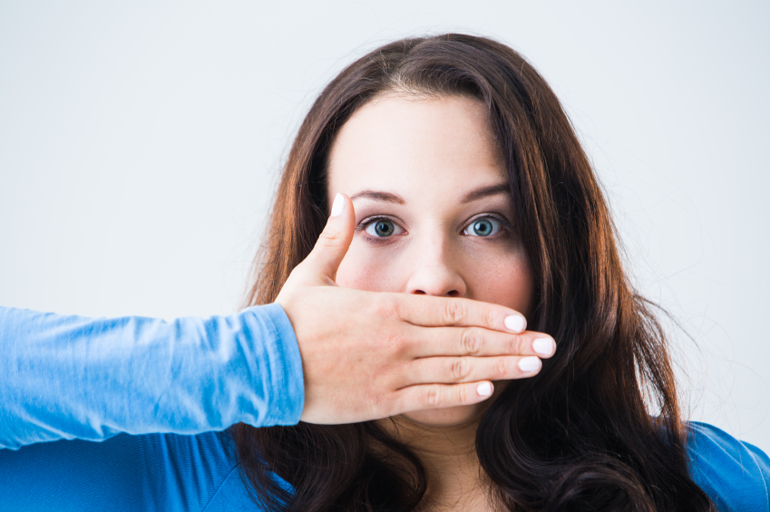 Surprised young woman covering her mouth with her hand.