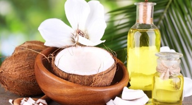 Coconuts and coconut oil on wooden table, on nature background